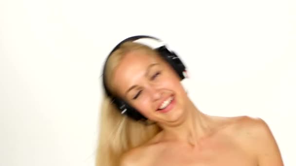 Красива жінка в навушниках слухає музику з мерехтінням на вітрове волосся на білому тлі — стокове відео