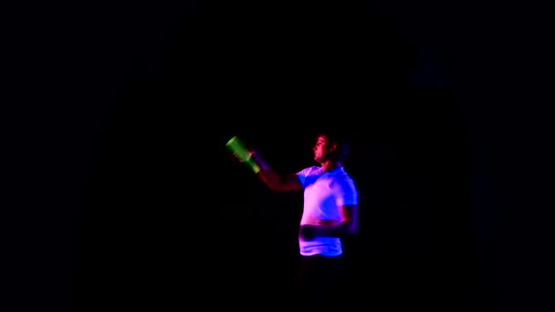 Бармен в белой футболке жонглирует бутылками на черном — стоковое видео
