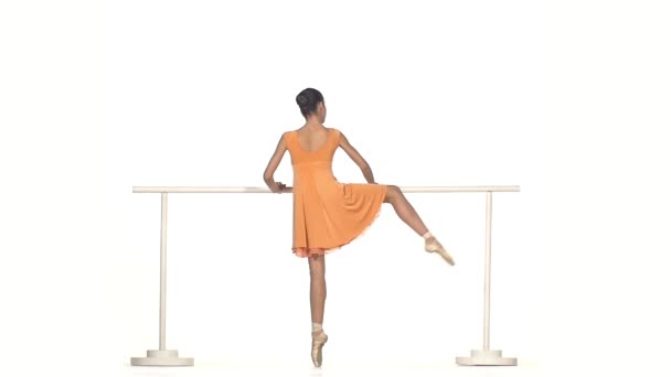 Молодая балерина в платье позирует на белом фоне — стоковое видео