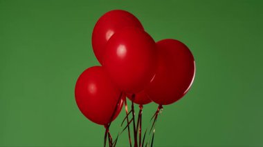 Birçok kırmızı balon krom anahtar efektli yeşil ekrana karşı havada asılı duruyor. Işık yansıtmalı parlak helyum balonlarını kapatın. Doğum günü, parti dekorasyonu, tatil, sürpriz, hediye, geçmiş.