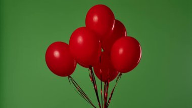 Birçok kırmızı balon krom anahtar efektli yeşil ekrana karşı havada asılı duruyor. Işık yansıtmalı parlak helyum balonlarını kapatın. Doğum günü, parti dekorasyonu, tatil, sürpriz, hediye, geçmiş.