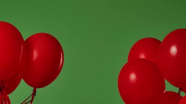 Birçok kırmızı balon krom anahtar efektli yeşil ekrana karşı havada asılı duruyor. Işık yansıtmalı parlak helyum balonlarını kapatın. Doğum günü, parti dekorasyonu, tatil, sürpriz, hediye, geçmiş.