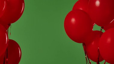 Birçok kırmızı balon krom anahtar efektli yeşil ekrana karşı havada asılı duruyor. Işık yansıtmalı parlak helyum balonlarını kapatın. Doğum günü, parti dekorasyonu, tatil, sürpriz, hediye, geçmiş.