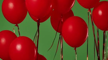 Birçok kırmızı balon krom anahtar efektli yeşil ekrana karşı havada asılı duruyor. Işık yansıtmalı parlak helyum balonlarını kapatın. Doğum günü, parti dekorasyonu, tatil, sürpriz, hediye, geçmiş.
