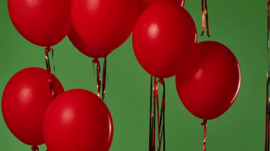 Birçok kırmızı balon krom anahtar efektli yeşil ekrana karşı havada asılı duruyor. Işık yansıtmalı parlak helyum balonlarını kapatın. Doğum günü, parti dekorasyonu, tatil, sürpriz, hediye, geçmiş.