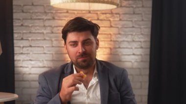 A businessman in a suit enjoys a delicious burger in a cozy cafe. An office worker relaxes and eats fast food during his lunch break.