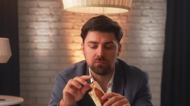 A businessman in a suit enjoys a delicious shawarma in a cozy cafe. An office worker relaxes and eats fast food during his lunch break.
