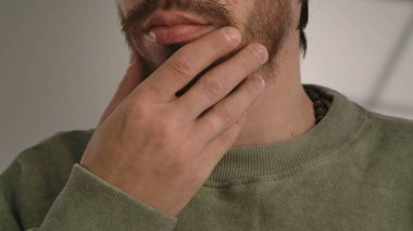 Sakallı, düşünceli bir jest sergileyen bir adamın el ve çene görüntüsü..