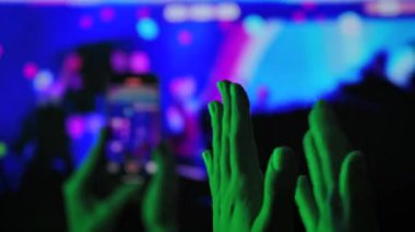 Bir konserde mavi arka planda kırmızı ışıkta el çırpmak. Parti, etkinlik, yeni yıl arifesi ve Noel için şenlikli bir ortam..