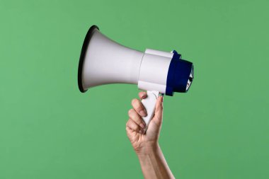 Yeşil krom anahtar arka planında megafon tutan bir kadın. Ofis, iş, eğitim, eğitim veya sosyal konularla ilgili tasarımlar için çekim.