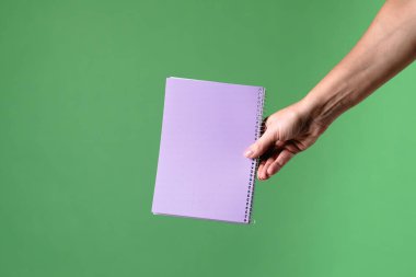 Yeşil krom anahtar arka planında mor bir defter tutan bir kadın. Ofis, iş, eğitim ve eğitimle ilgili tasarımlar için çekim.