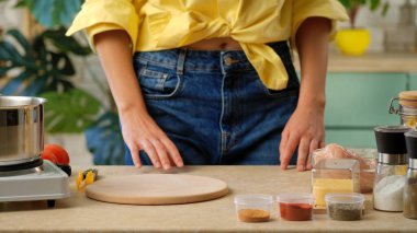 Kadın mutfakta yemek yapmaya hazırlanıyor. Baharatlar, tavuk ve sebzeler tezgahta..