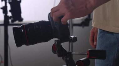 Profesyonel bir SLR kamerasını bir film stüdyosundaki ışıklandırma ve arka plan ekipmanlarıyla tamir edip ayarlayan bir adam. Çekimden önce teknik hazırlık sahnesi.