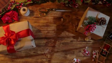 Noel Baba 'nın eldivenli ellerinin sade ahşap bir masada hediye kutuları düzenleyişinin en üst görüntüsü. Yılbaşı ve Noel kutlamaları için hazırlıklar.