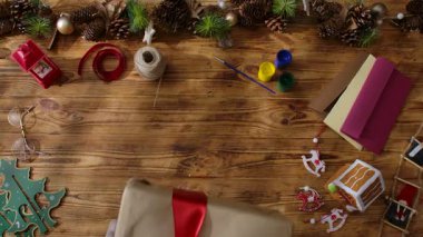 Noel Baba 'nın eldivenli ellerinin sade ahşap bir masada hediye kutuları düzenleyişinin en üst görüntüsü. Yılbaşı ve Noel kutlamaları için hazırlıklar.