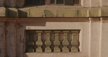 Paslı demir ızgaralı ve soyulmuş boyalı, gökyüzünü ve ağaçları yansıtan eski bir pencerenin detaylı bir görüntüsü. Zamanın geçişine ve mimari bozulmaya dokulu bir bakış..