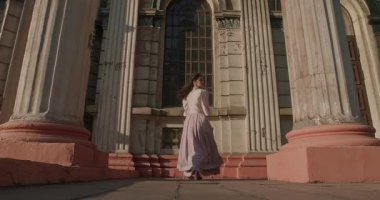 Tarihi kostümlü bir kadın bir mektubu öpüyor ve yumuşak akşam ışığı tarafından aydınlatılan antik mimarinin arka planına karşı gizli bir yere saklıyor..