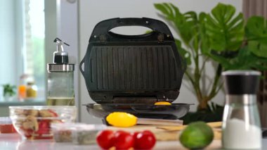 Yumurta, sebze ve mutfak gereçleri ile kahvaltı hazırlamak için hazırlanmış bir ev mutfağı manzarası. Bir kadın iki yumurta pişiriyor..