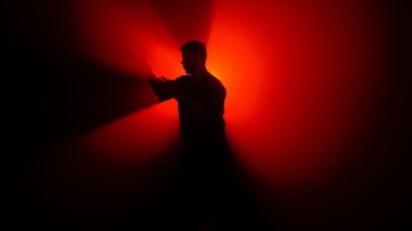 Bir dövüş sanatları ustasının karanlık figürü yeteneklerini geliştirir, güçlü bir kırmızı ışığın önünde çeşitli duruşlar sergiler, dramatik aydınlanma ışınları yaratır..