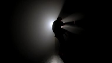 Bir dövüş sanatları ustasının karanlık figürü yeteneklerini geliştirir, güçlü beyaz bir ışığın önünde çeşitli duruşlar sergiler, dramatik aydınlanma ışınları yaratır..