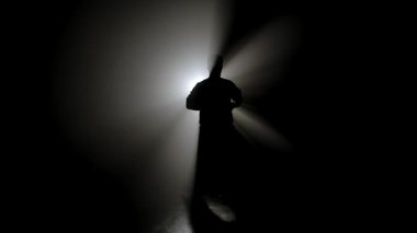 Bir dövüş sanatları ustasının karanlık figürü yeteneklerini geliştirir, güçlü beyaz bir ışığın önünde çeşitli duruşlar sergiler, dramatik aydınlanma ışınları yaratır..