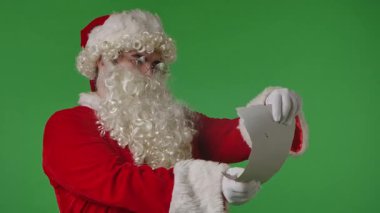 Noel Baba yeşil renkli anahtar arka planında bir mektup okuyor. Noel temalı kompozisyonlar için ideal.