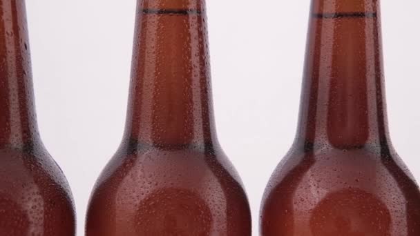 Конвейерные бутылки пива с капельками на белом фоне — стоковое видео