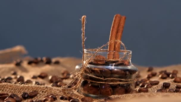 Little bottle with coffee beans and cinnamon on sacking, close up, gray background — Stock Video