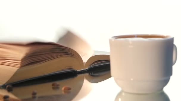 Xícara de café delicioso, leite com livro de páginas giratórias isolado em fundo branco — Vídeo de Stock