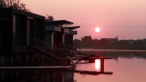 Východ slunce nad řekou nedaleko domy — Stock video