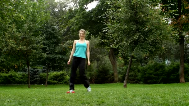 Фітнес-тренування жінка використовує гантелі в тренуваннях з фізичної сили на вулиці на траві. Інструкторські вправи з невеликими вагами в зеленому парку . — стокове відео