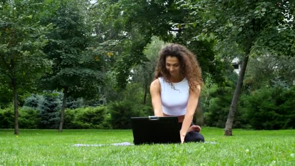 Ung kvinna yoga i parken arbetar på en bärbar dator — Stockvideo