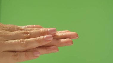 Canlı yeşil bir arka planda cilde nemlendirici krem sürerken elinizi kapatın. Güzellik konsepti, cilt bakımı ve krem ürün sunumu.