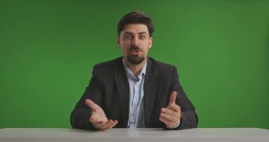 Takım elbiseli bir adam yeşil bir geçmişi olan canlı yayın stüdyosunda oturuyor ve bilgi ya da haber sunuyor. Medya üretimi için ideal.