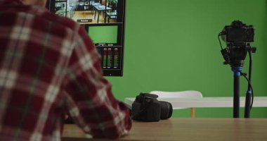 Gelişmiş ekipmanlarla yeşil ekranın önünde bir sunucunun yer aldığı modern bir canlı yayın stüdyosu. Takım elbiseli bir adam bilgi ya da haber sunar. Medya üretimi için ideal.