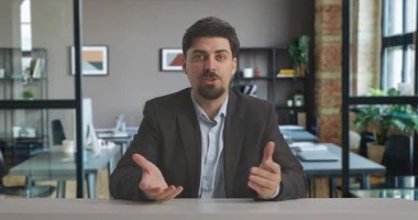 Takım elbiseli bir adam güvenli bir şekilde profesyonel canlı yayın stüdyosunda oturuyor ve modern ofis ortamında yayınlanmaya hazır. Bir adam bilgi ya da haber sunar. Medya üretimi için ideal.