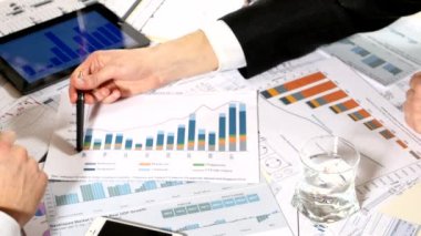 masada oturan iş grafiklerini tartışan, bir iş projesi geliştiren ve piyasa veri bilgilerini analiz eden erkekler