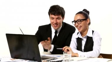 İş adamları dizüstü bilgisayara bakarak fikirleri tartışıyorlar, canlı bir şekilde gesturing. Yüzlerindeki gülümsemeler