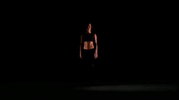 Девушка выходит из тени и танцы созерцают на черном фоне, пятна света — стоковое видео