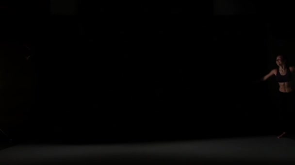 黒い背景、スローモーションの影の中で踊る笑顔の女の子のジャンプ — ストック動画