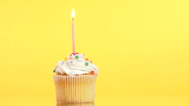Tasty birthday cupcake with one candle, on yellow background — Stock Video