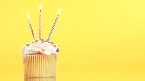 Вкусный кекс на день рождения с тремя свечами, на желтом фоне — стоковое видео