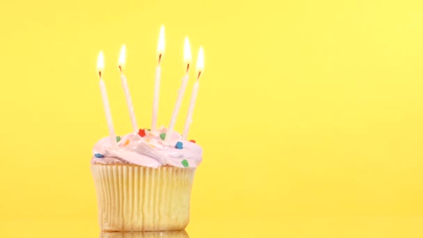 Sabroso cupcake de cumpleaños con cinco velas, sobre fondo amarillo — Vídeo de stock