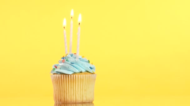 Cupcake de aniversário saboroso com três velas, no fundo amarelo — Vídeo de Stock