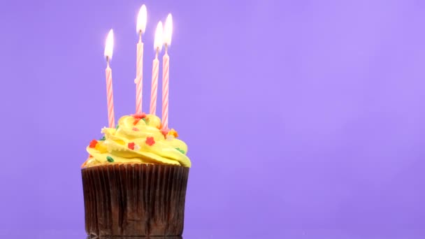 Smakelijke verjaardag cupcake met vier kaars, op paarse achtergrond — Stockvideo