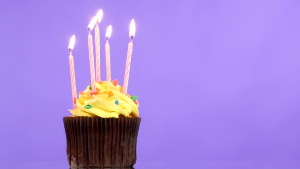 Sabroso cupcake de cumpleaños con cinco velas, sobre fondo púrpura — Vídeos de Stock