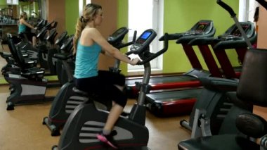 Atletik ve çekici kız fitness salonunda Bisiklete binme