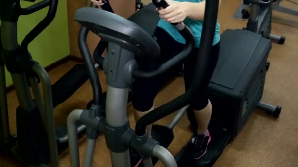 Chica atlética haciendo un ejercicio en pista de fitness en el gimnasio, cámara lenta, cam se mueve hacia arriba — Vídeo de stock