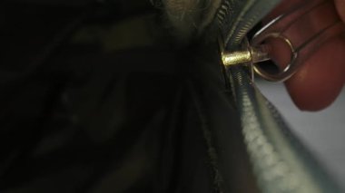 Makro çekim, bavulun içinden görüntü, plastik bir fermuarı parlak ışıklı bir odada metal çekiş sekmesiyle bağlamak..