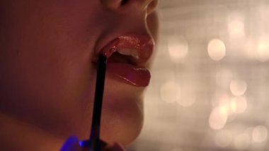 Dudakların parlak dudak parlatıcısıyla kaplandığı detaylı bir yakın plan, göz alıcı ve şehvetli bir görünüm sergiliyor..